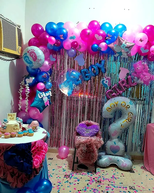 Gender reveal: pink and blue garland, foil balloons and cake table