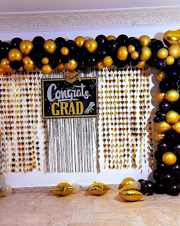 Graduation wall: black and gold garland with a hand-lettered sign